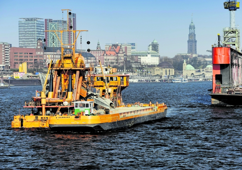 Mehr Schlick in der Elbe als gedacht: Ein Baggerschiff im Einsatz im Hafen vor der Hamburger Stadtkulisse 