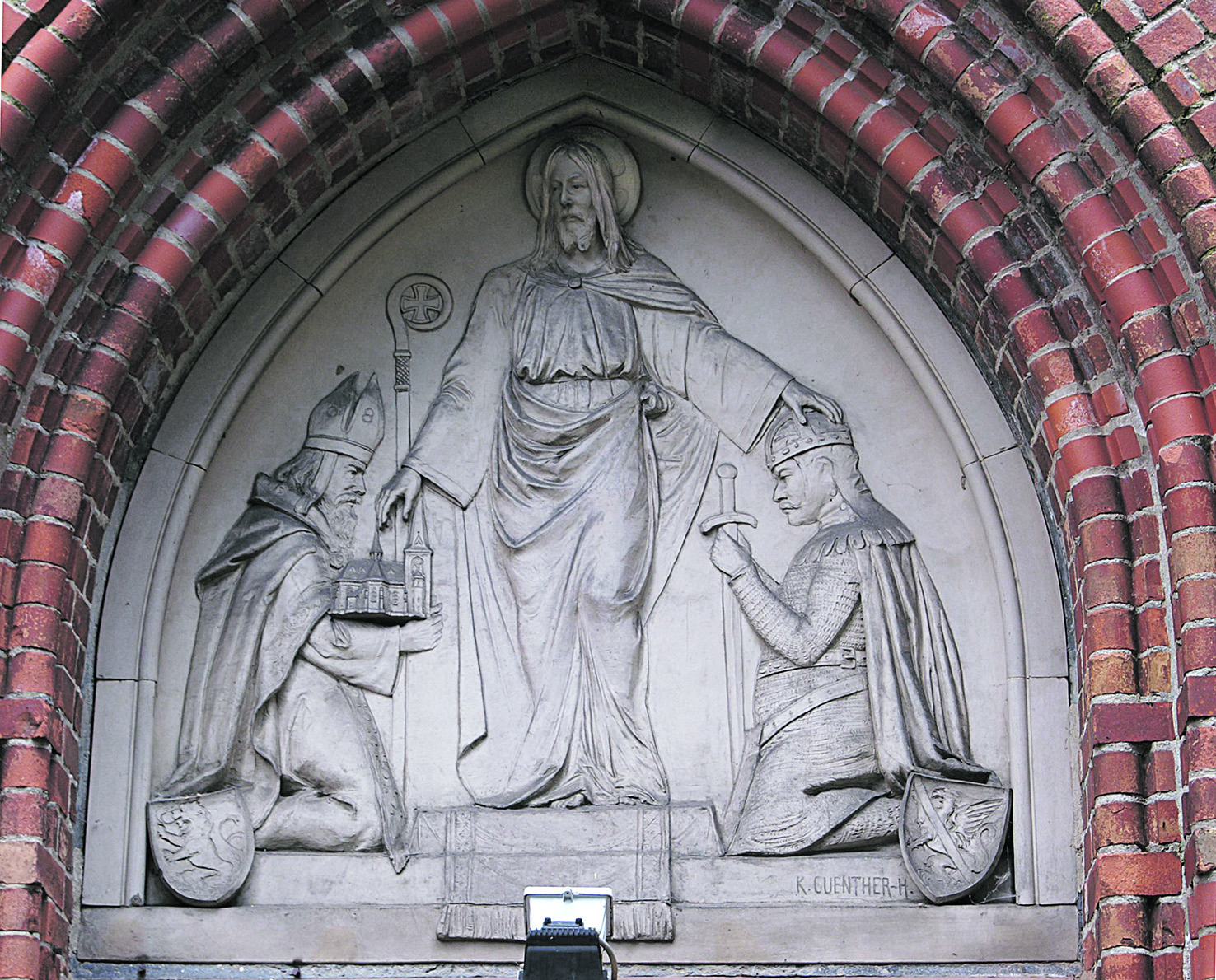 Relief über dem Portal der Wartislaw-Gedächtniskirche in Stolpe an der Peene: Jesus Christus legt Wartislaw I. die Hand auf das Haupt, Bischof Otto von Bamberg präsentiert das Modell der Kirche 