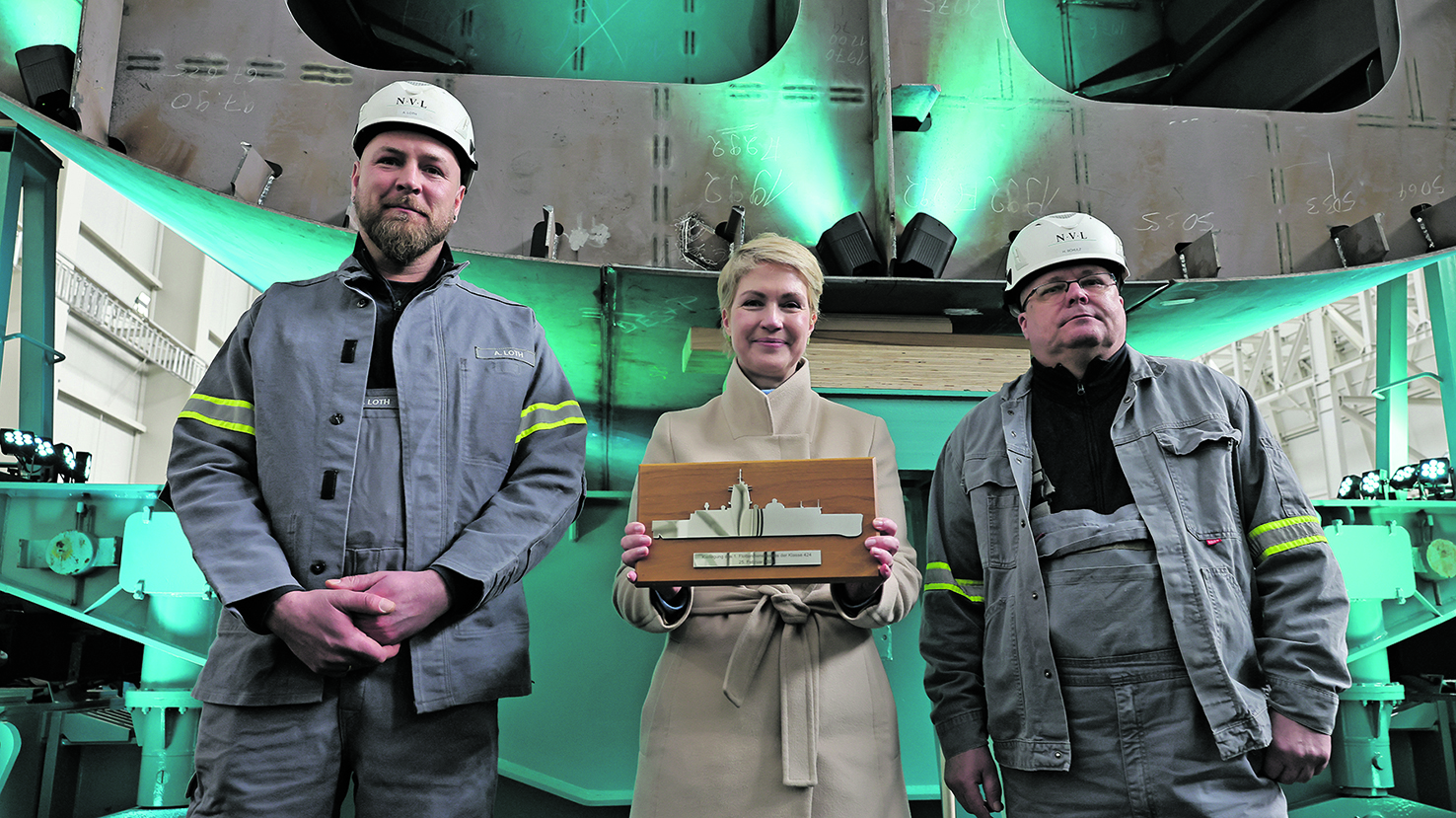 Die beiden direkt mit dem Bau der drei zukünftigen Marineschiffe beschäftigten Wolgaster Schiffbauer Heiko Schulz (links) und Schweißer André Loth (rechts) schoben gemeinsam mit der Ministerpräsidentin von Mecklenburg-Vorpommern, Manuela Schwesig (SPD), d