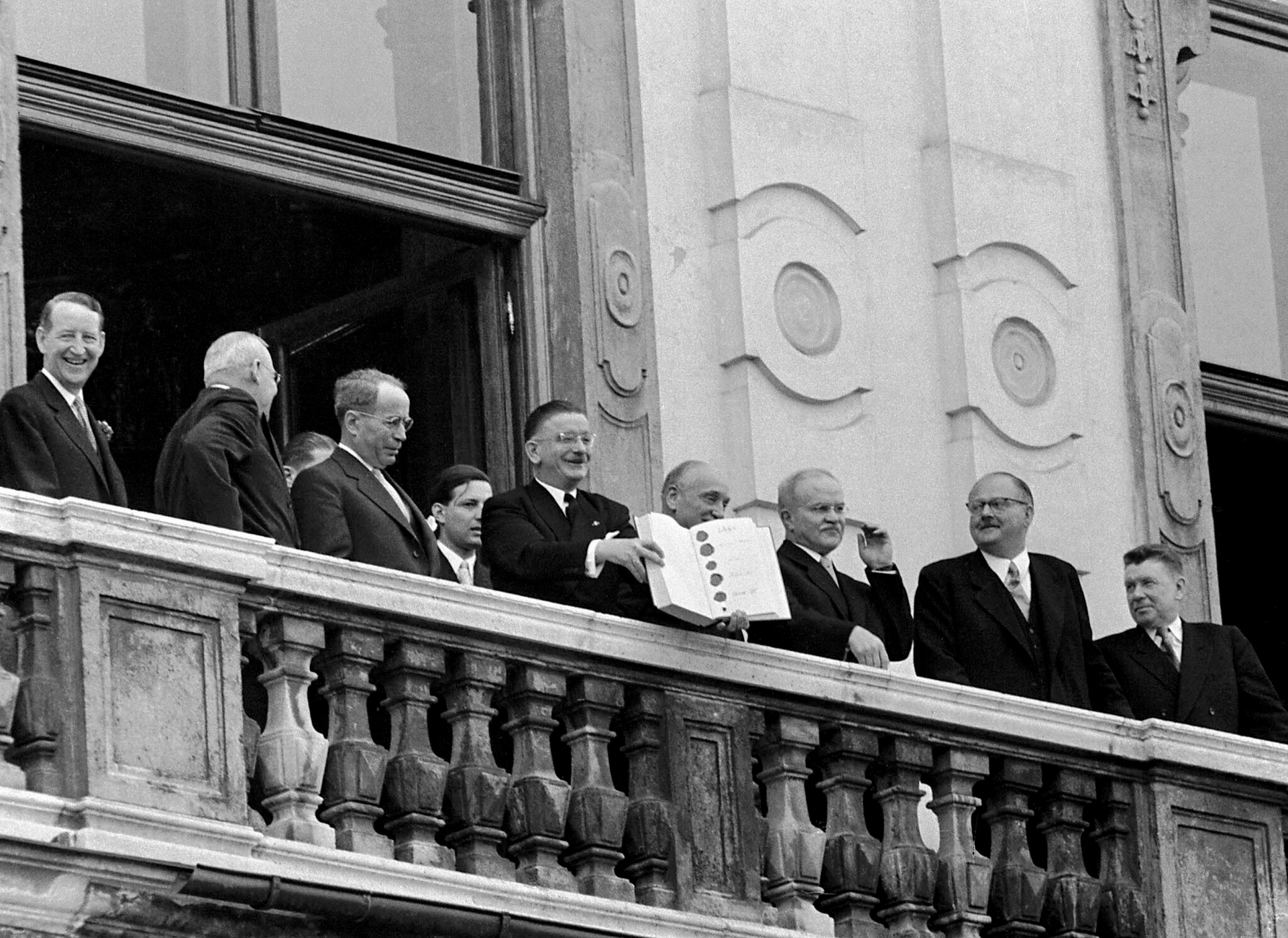 Nach der Unterzeichnung: Österreichs Außenminister Leopold Figl zeigt im Beisein von Vertretern der Alliierten der wartenden Menge den Staatsvertrag