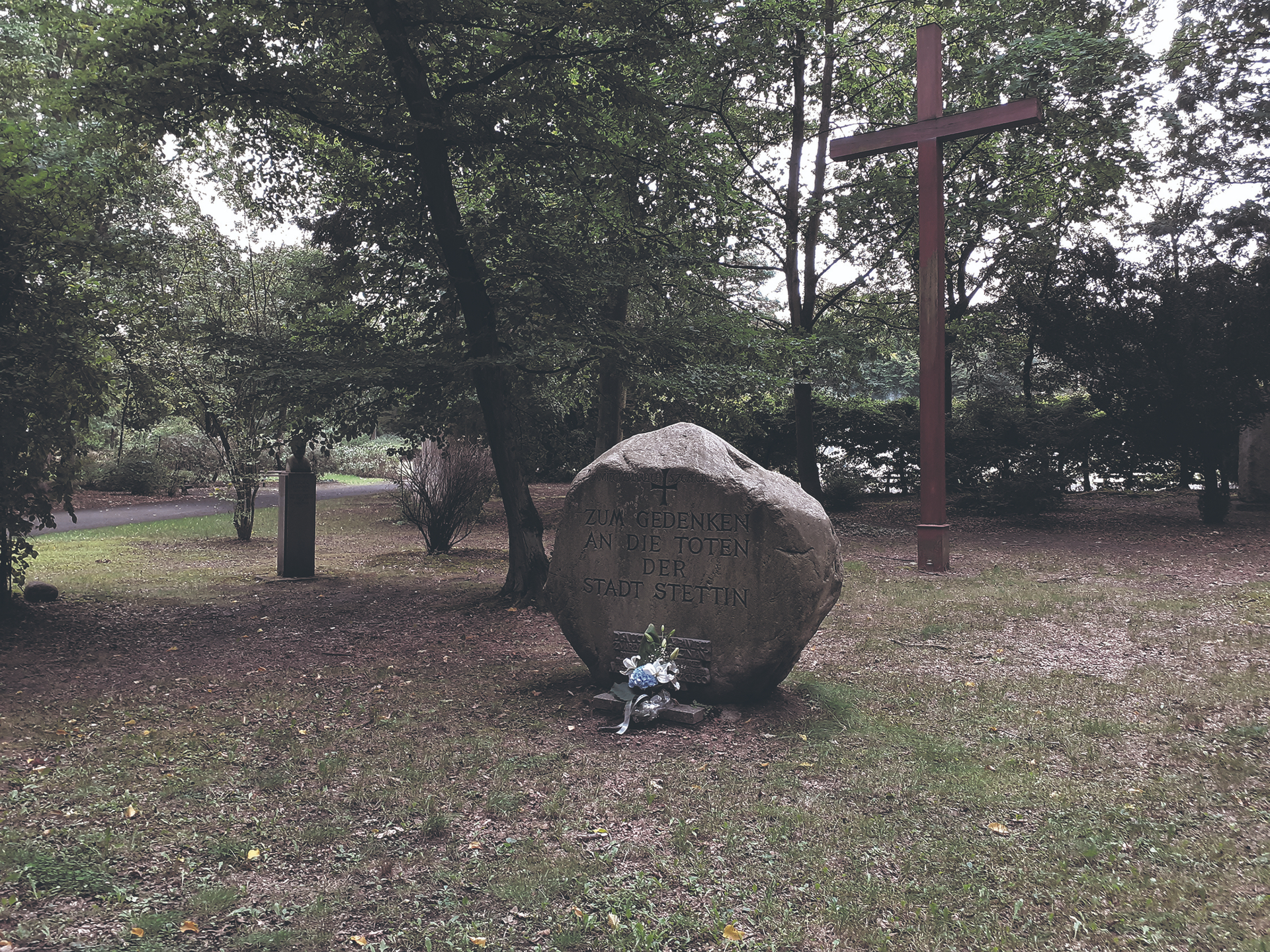 Auf dem Hauptfriedhof (heute Zentralfriedhof) in Stettin: Der Gedenkstein für die Toten der Stadt Stettin, errichtet im Jahr 1996, das Kreuz im Jahr 2001. Der Findling wurde an der Ostseeküste bei Kolberg geborgen